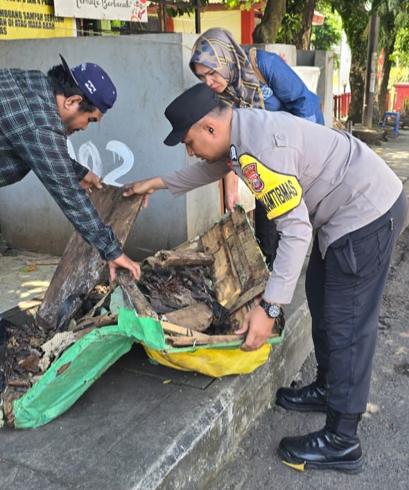 Bhabinkamtibmas bersama lurah melakukan pembersihan trotoar.