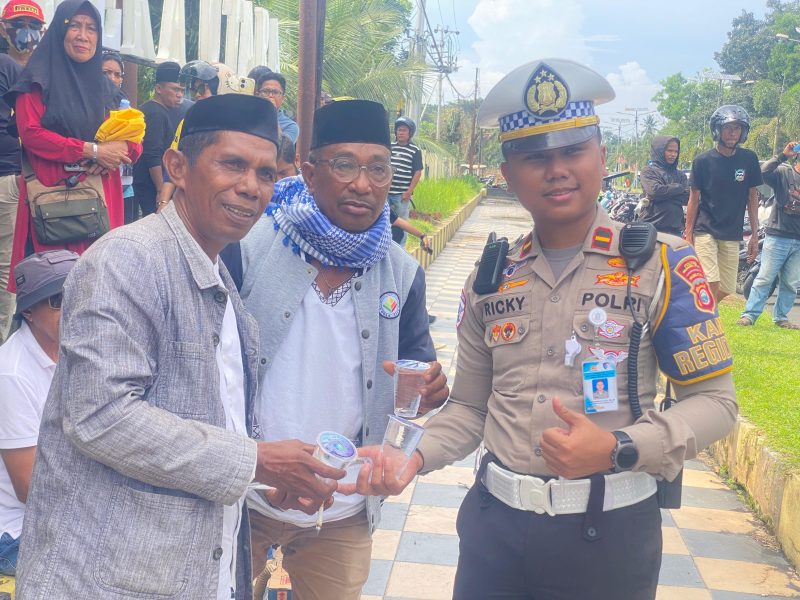 Kanit Rekiden Ipda Rucky Richardo bersama persinil Satlantas Polres Halut bagikan air mineral ke masa aksi.(istimewa)